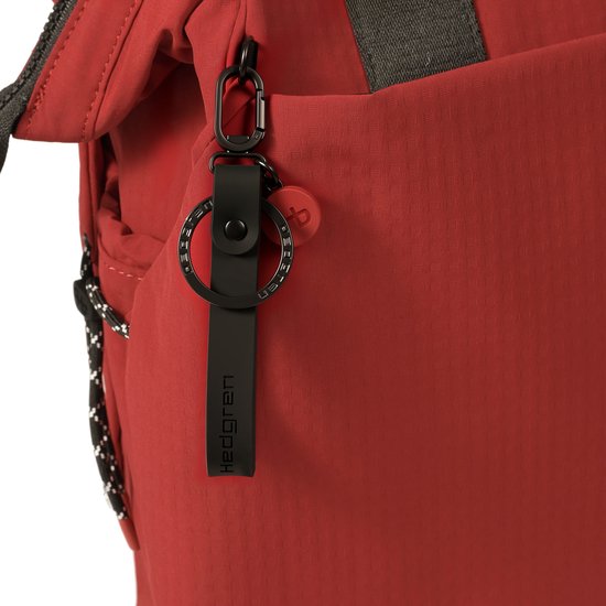 Detail van de rode Hedgren rugzak met zwarte sleutelhanger en karabijnhaak.