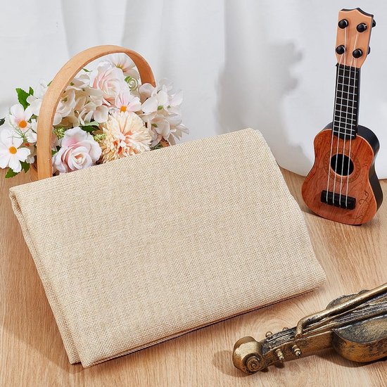 Beige linnen stof op een tafel, met een mand bloemen en een speelgoedgitaar.