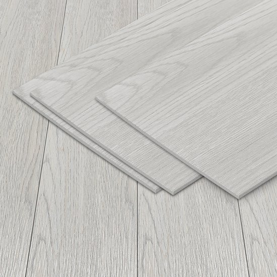 Een stapel lichtgrijze PVC vloerplanken met houtnerf ligt op een gelegde vloer.