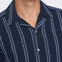 Detail van een donkerblauw overhemd met verticale strepen en knopen.