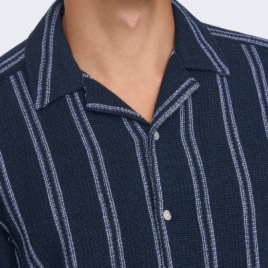 Detail van een donkerblauw overhemd met verticale strepen en knopen.