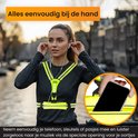 Vrouw met een neongeel R2B hardloopvest met LED-verlichting en opbergvak waaruit ze een smartphone haalt.
