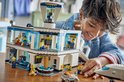 Jongen bouwt LEGO City Luchthaven met Vliegtuig (60502). Het gebouw is wit met blauwe accenten en heeft veel raampjes.