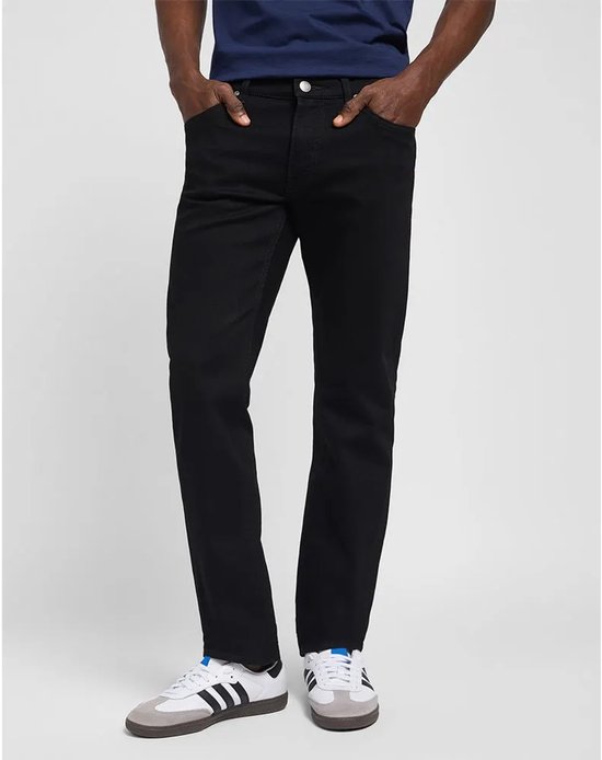 Man in donkerblauwe top en zwarte jeans, met witte sneakers met strepen.