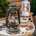 Bronzen Feuerhand stormlantaarn met vlam, op een dienblad met koffie en noten.