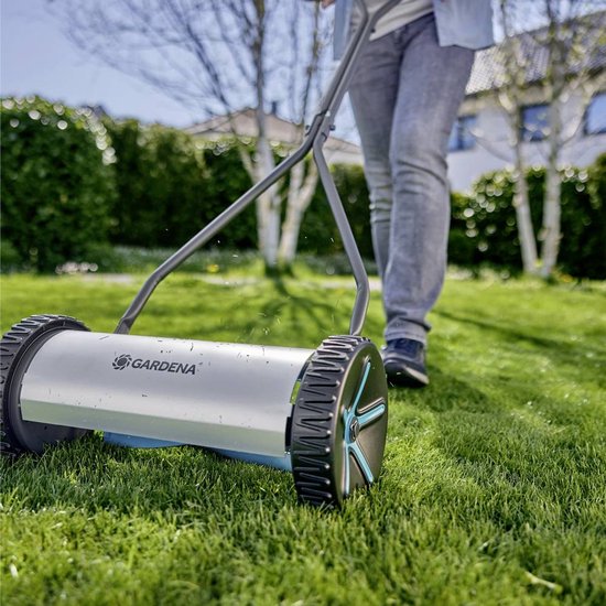 Persoon maait gras met GARDENA kooimesmaaier op een zonnige dag.