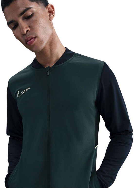 Model in donkergroene en zwarte Nike jas met ritssluiting.