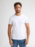 Model draagt een wit T-shirt met korte mouwen en een blauw logo op de borst.