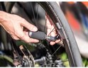 Handen gebruiken een zilveren CO2-patroon met zwarte hoes om een fietsband op te pompen.