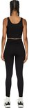 Zicht op de achterkant van een model met zwarte crop top en zwarte, nauwsluitende sportlegging met hoge taille en geribd patroon.