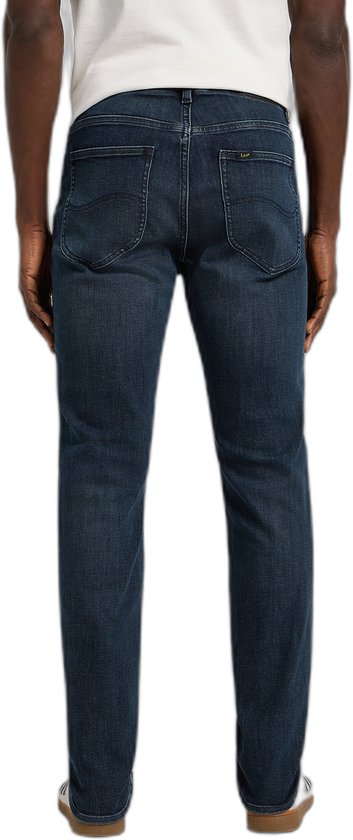 Achterkant van een man in donkerblauwe slim fit jeans met Lee logo op achterzak en leren patch op tailleband.