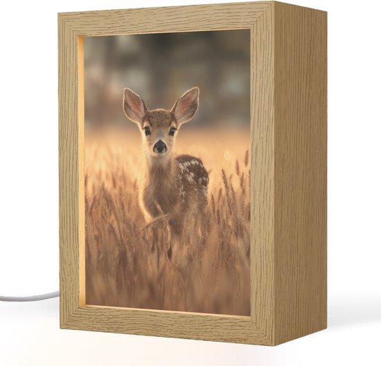 Een houten lijst met een hert in een graanveld, met warme verlichting en een witte kabel.