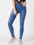Model in lichtblauwe skinny jeans en witte sneakers. Vooraanzicht.