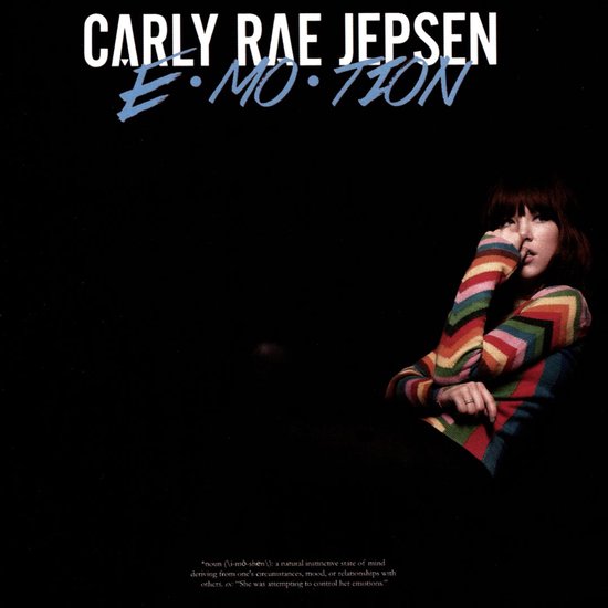 Carly Rae Jepsen albumhoes met tekst 'Emotion' en zangeres met gebreide trui met regenboogpatroon.