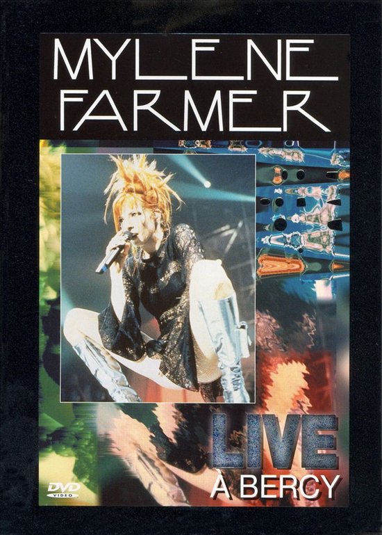 Mylène Farmer Live à Bercy DVD: zangeres met rood haar en zilveren laarzen, draagt zwarte kanten jurk.