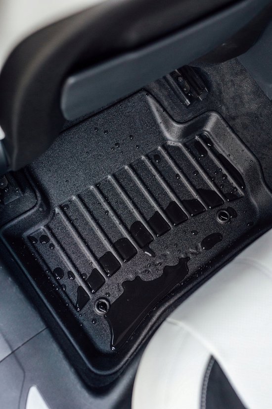 Gedetailleerde close-up van een natte, zwarte Proline 3D-vloermat geïnstalleerd in de auto, met water op de ribbels.