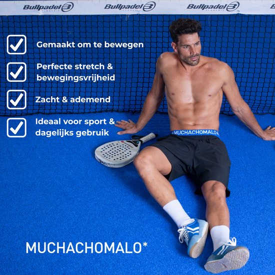 Man zit op een blauwe sportvloer, naast een padelracket. Hij draagt zwarte Muchachomalo boxershorts met blauwe band. Checklist met 'Gemaakt om te bewegen'.
