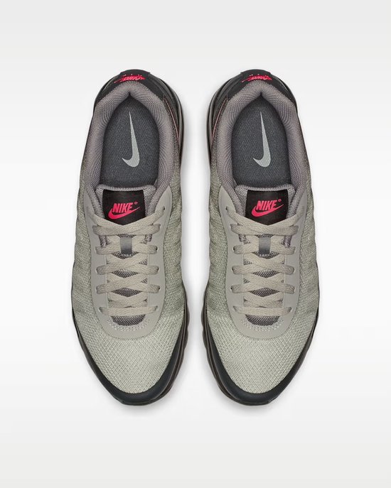 Grijze Nike sneakers met roze Nike logo's en veters.