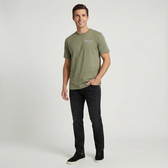 Man in olijfgroen Cars Jeans T-shirt met kleine tekst op de borst en zwarte jeans.