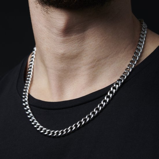 Close-up van een man die een zilverkleurige schakelketting om zijn nek draagt.