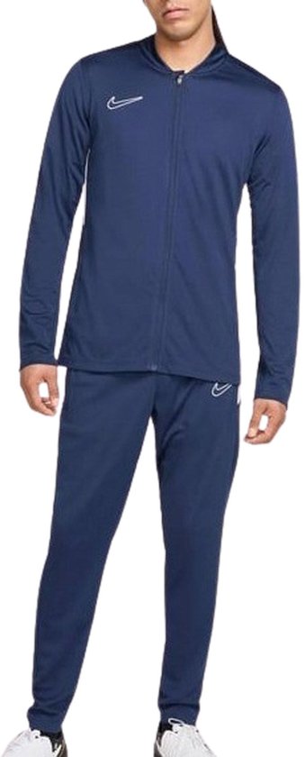 Marineblauw Nike trainingspak met ritssluiting, witte Nike logo's op jack en broek.