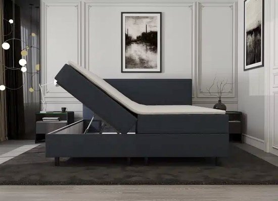 Donkergrijze boxspring met verstelbaar matras, liggend op een mat.