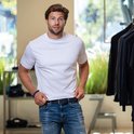Homme portant un t-shirt blanc, un jean, une ceinture bleue et un bracelet de perles.
