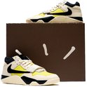 Hoge beige sneakers met limegroene accenten en zwarte Swoosh, naast een bruine doos.