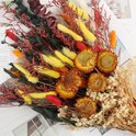 Gedetailleerd boeket van gedroogde bloemen in herfsttinten met diverse grassen, pluimen en zonnebloemen.