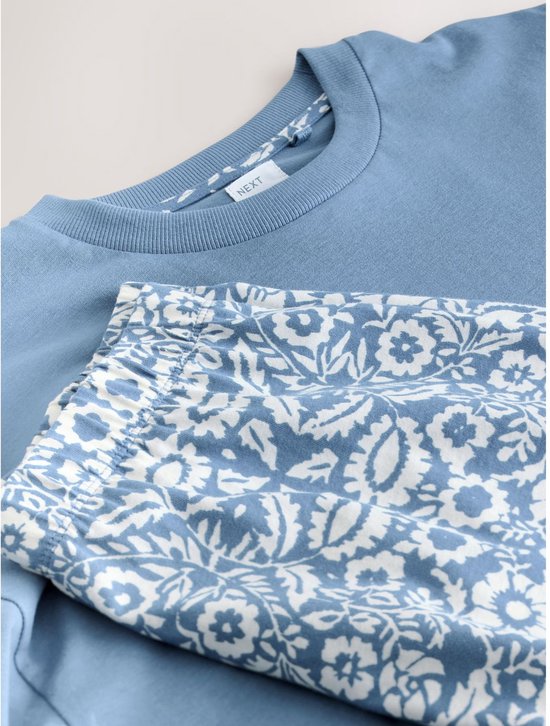 Blauw t-shirt met label 'NEXT' en korte pyjamabroek met bloemenprint.