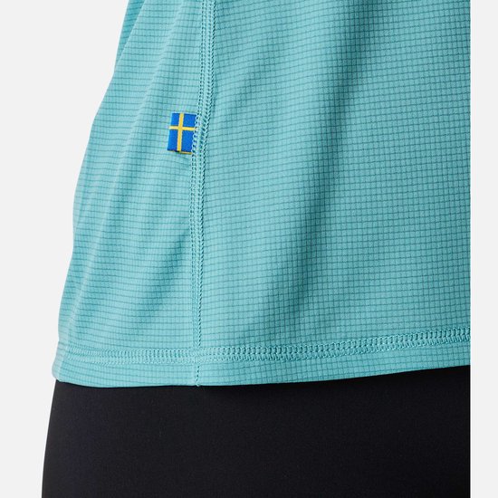 Detail van turquoise sportshirt met gestructureerd weefsel en Zweedse vlag patch.