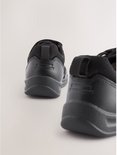 Achterkant van een paar zwarte sneakers met klittenbandsluiting en elastische veters.