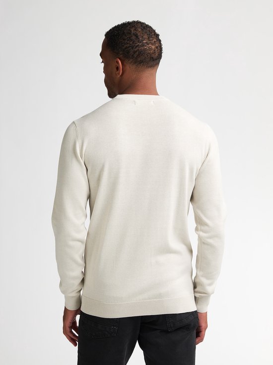 Man met beige trui met lange mouwen, rug zichtbaar.