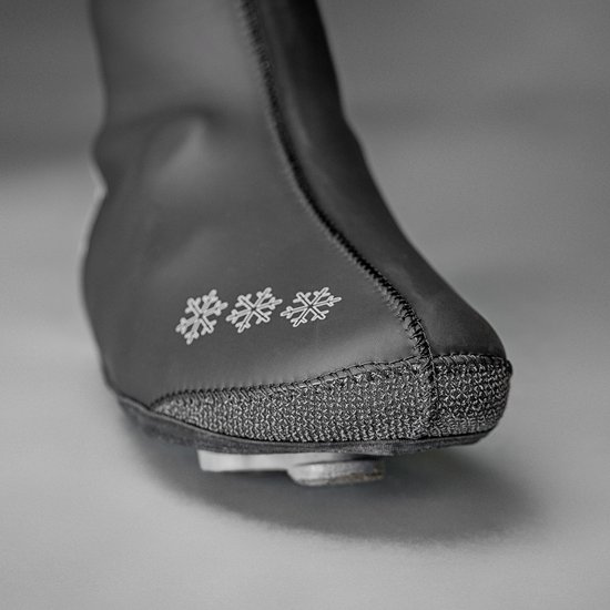 Close-up van de neus van een zwarte "GripGrab" overschoen met sneeuwvlokken en verstevigde zool.