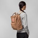 Vrouw draagt bruine Fjallraven Kanken rugzak op de rug.