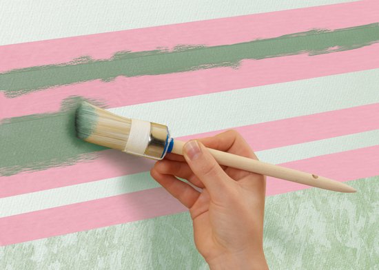 Vrouw brengt tape aan op een muur met gekleurde regenboog van roze, gele, groene en blauwe banen.