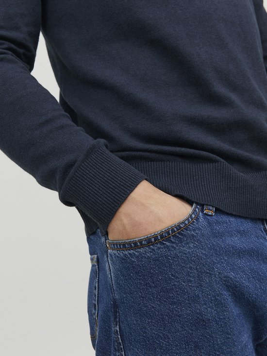 Donkerblauwe gebreide trui met coltrui en een hand in de jeanszak.