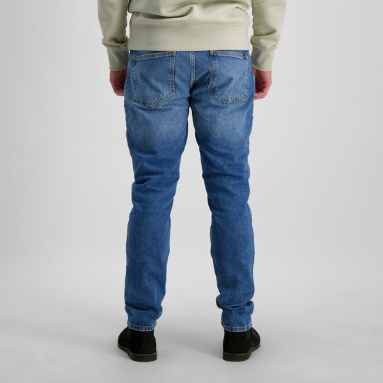 Vue arrière d'un mannequin portant un jean bleu délavé clair et des chaussures noires.