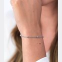 Zilverkleurige armband met dunne ketting en subtiele bolletjes, gedragen door een vrouw.