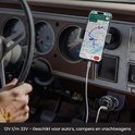 Een man rijdt een auto met een navigatiesysteem en een autolader die een telefoon oplaadt.