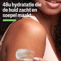 Een vrouw brengt witte crème aan op haar arm. 48u hydratatie die de huid zacht en soepel maakt. Lichte hydratatie.