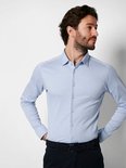 Homme mains sur les hanches, portant une chemise Desoto bleu clair.