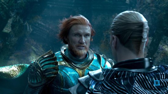 Man met rood haar en baard, draagt een turquoise harnas. Hij kijkt naar een man met donker haar.