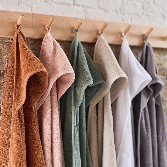 Zes badcapes in verschillende kleuren (bruin, roze, groen, beige, wit, grijs) hangen aan een houten rek.