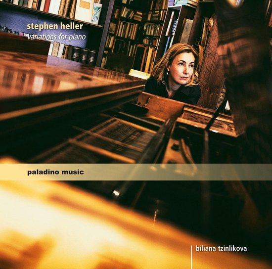 Een blondharige vrouw met oorbellen in een zwart shirt, staand bij een vleugel in een bibliotheek.
