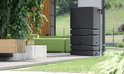 Antracietkleurige regenton met ribbelstructuur, naast een groene bank en planten.