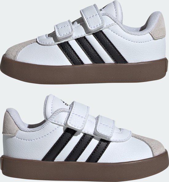 Twee witte adidas sneakers met bruine zolen en klittenbandsluitingen.