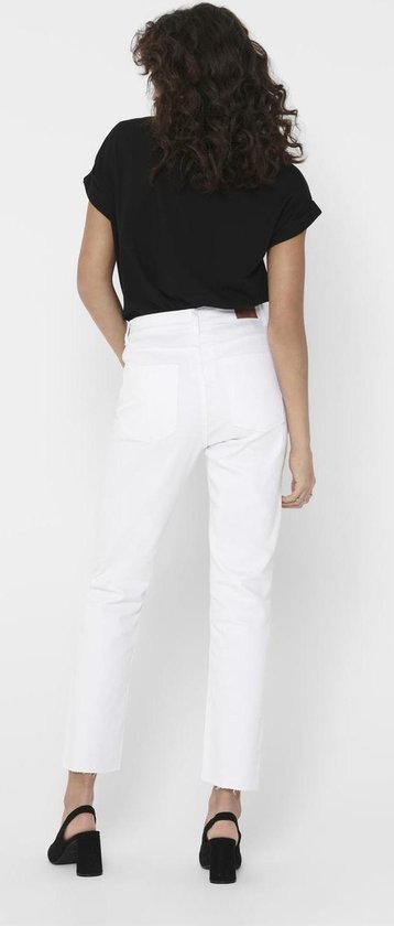 Vrouw van achteren gezien, draagt een zwarte top met opgerolde korte mouwen en een witte jeans met rafels aan de onderkant.