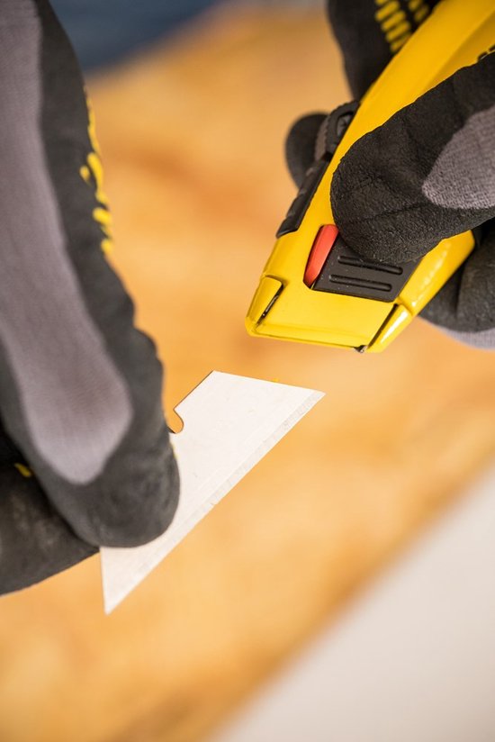 Grijze werkhandschoenen wisselen een mesje van een geel Stanley Fatmax schuifmes.