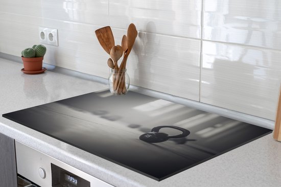 KitchenYeah® Inductie beschermer 76x51.5 cm - Verschillende kettlebellgewichten op de vloer in een fitnessruimte - Kookplaataccessoires - Afdekplaat voor kookplaat - Inductiebeschermer - Inductiemat - Inductieplaat mat